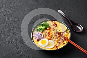 Ohn No Khao Swe in black bowl at dark slate background. Oh No Khao Suey is Coconut Milk Noodle Soup of myanmar cuisine photo