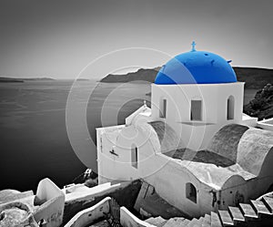 Oia town on Santorini island, Greece. Blue dome church, black and white.