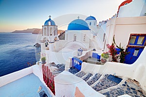 Oia town on Santorini island, Greece at sunset. Rocks on Aegean sea.