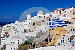 Oia town on Santorini island, Greece. Waving Greek flag