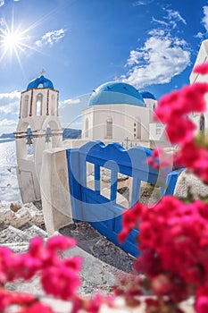 Oia village with churches against red flowers on Santorini island in Greece