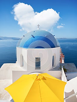 Oia village, Santorini Island, Greece. A cloud in the shape of a heart. A blue sky and a heart sign. View of traditional houses an