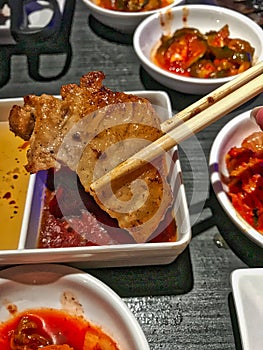 A oiece of pork in chopsticks, Korean BBQ
