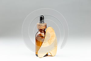 Oil bottle and gua sha wooden massager over gray