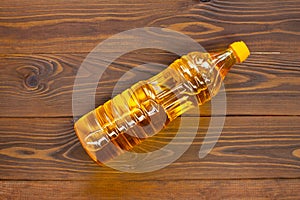 Oil in a bottle on the table. Olive oil in a plastic bottle with a yellow cap lies on brown wooden boards. A bottle of sunflower