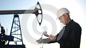 Oil business. Engineer next to an oil rig signs a paper contract. Oil production industry finance concept. Gas