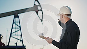 oil business. engineer next to an oil rig signs a paper contract. oil production industry finance concept. gas