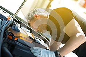 Oil change in car. Man repairing the engine in the car. Self-changing oil in own car. Man looks under the hood of his auto