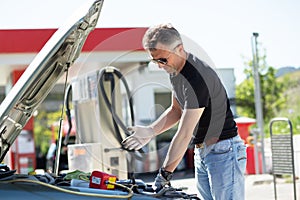 Oil change in car. Mature man repairing the engine in the car. Self-changing oil in own car. Man looks under the hood of his auto