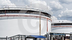 Oil depot storage tanks. Large white Industrial tanks for petrol and oil on dramatic sky background