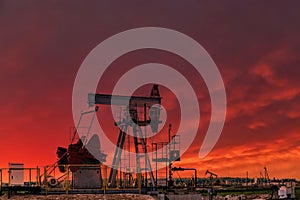 Oil drill rig and pump jack at sunset background.