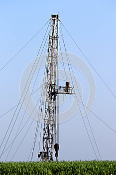 Oil drilling rig behind green wheat