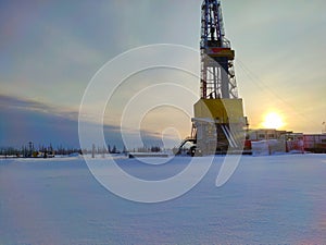 Oil drilling rig. Winter at dawn in the snow