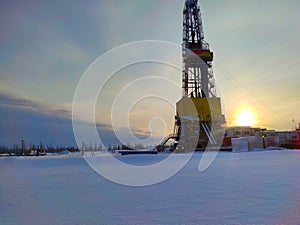 Oil drilling rig. Winter at dawn in the snow