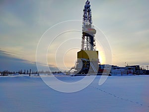 Oil drilling rig. Winter at dawn in the snow