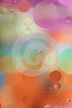 Oil drops in water on a colored background. Bright background with pink, orange and green circles of different sizes.