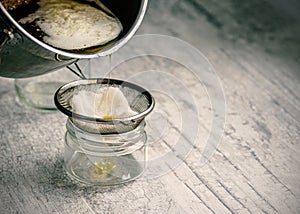 The oil is filtered into a glass jar through a metal sieve