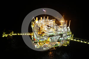 Oil and gas construction in night view. View from helicopter night flight. Oil and gas platform in offshore.