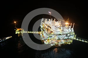 Oil and gas construction in night view. View from helicopter night flight. Oil and gas platform in offshore.