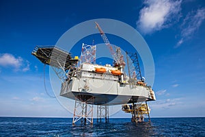 Oil and Gas drilling rig working on remote wellhead platform, prepare to transfer passenger by personal basket photo