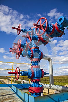 Oil, gas industry. Group wellheads and valve armature, Gas valve, Gas well of high pressure, against the blue sky with clouds,
