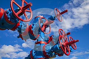 Oil, gas industry. Group wellheads and valve armature, Gas valve, Gas well of high pressure, against the blue sky with clouds