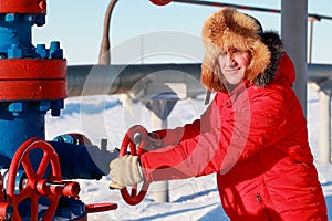 Oil and gas industry. A man in a red jacket opens a gas well to work