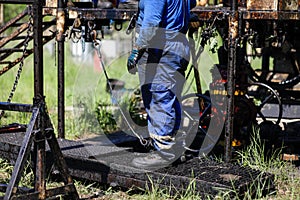 Oil and gas industry worker operates oil rig drill pipes on an oil well rig