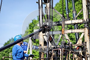 Oil and gas industry worker operates oil rig drill pipes on an oil well rig