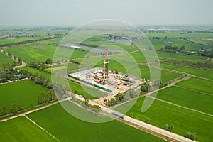 Oil and gas land drilling rig onshore in the middle of a rice field