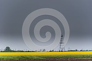Oil and gas well rig, outlined rural canola field
