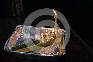 Oil Hanukkah candles and a wax shamash alight in an aluminum pan in Jerusalem, Israel.