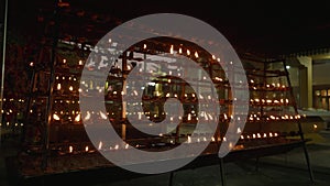 Oil lamps at Buddhist temple. Oil lamp worshipper lighting at stupa. Outdoor night 4k footage. Offering place in Sri