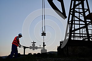 Oil man using petroleum pump jack in oil field.