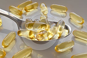 Oil pills or Fish oil or Evening primrose oil supplement capsules on spoon.