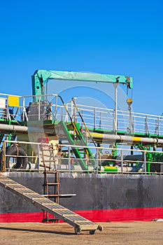 Oil pipeline system with crane machinery in tanker ship during renovation work in shipyard area at harbor