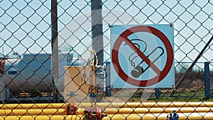 Oil plant. Warning on the fence about the ban on smoking. Danger of open fire. Oil and gas industry. Storage tanks for