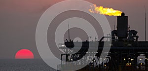 Oil platform and flare at sunset