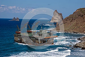 Oil platform lifted by storm on rocky coast - threatened by strong winds in the seas