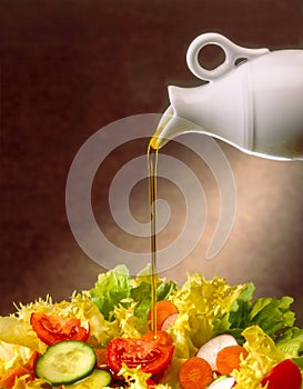 Oil poured from a white cruet over a salad of tomatoes, cucumbers and vegetables