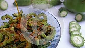Oil pouring on Karela slices mixed with Haldi to make Achaar - Indian recipe