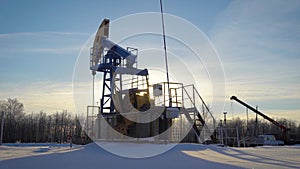 Oil production plant is pumping petroleum from ground in winter day, huge industrial equipment