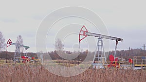 Oil production in Russia. Two working oil pumps against the background of an autumn forest in cloudy windy and rainy weather