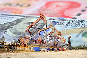 Oil pump on background of US dollar and RMB