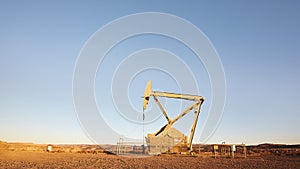 Oil pump on a desert at sunset