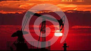 Oil pump jack against red sunset