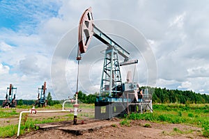 Oil pump jack in the field in Russia under cloudy skies