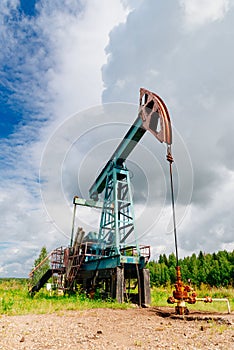 Oil pump jack in the field in Russia under cloudy skies