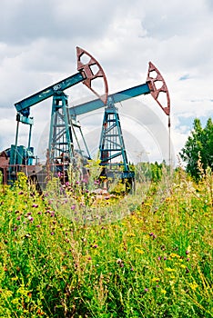 Oil pump jacks in the field in Russia under cloudy skies
