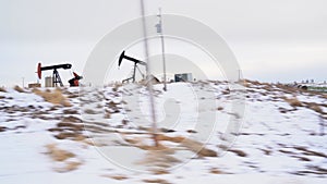 Oil pump jacks during the winter in a farm field of the Canadian prairies